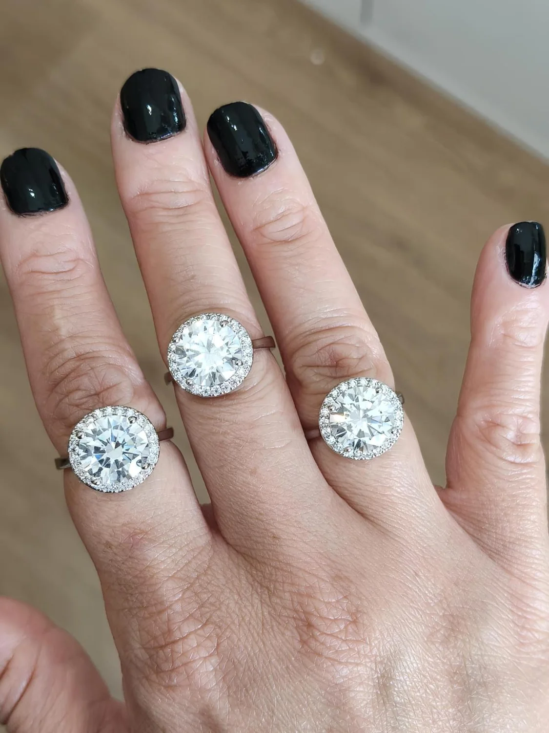 Anéis de moissanite na mão com unhas pretas